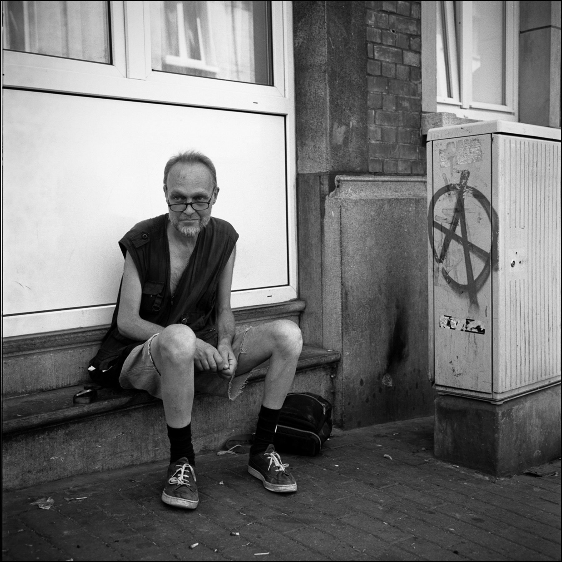 homme-lunettes-short-assis-symbole-anarchie-noir-et-blanc