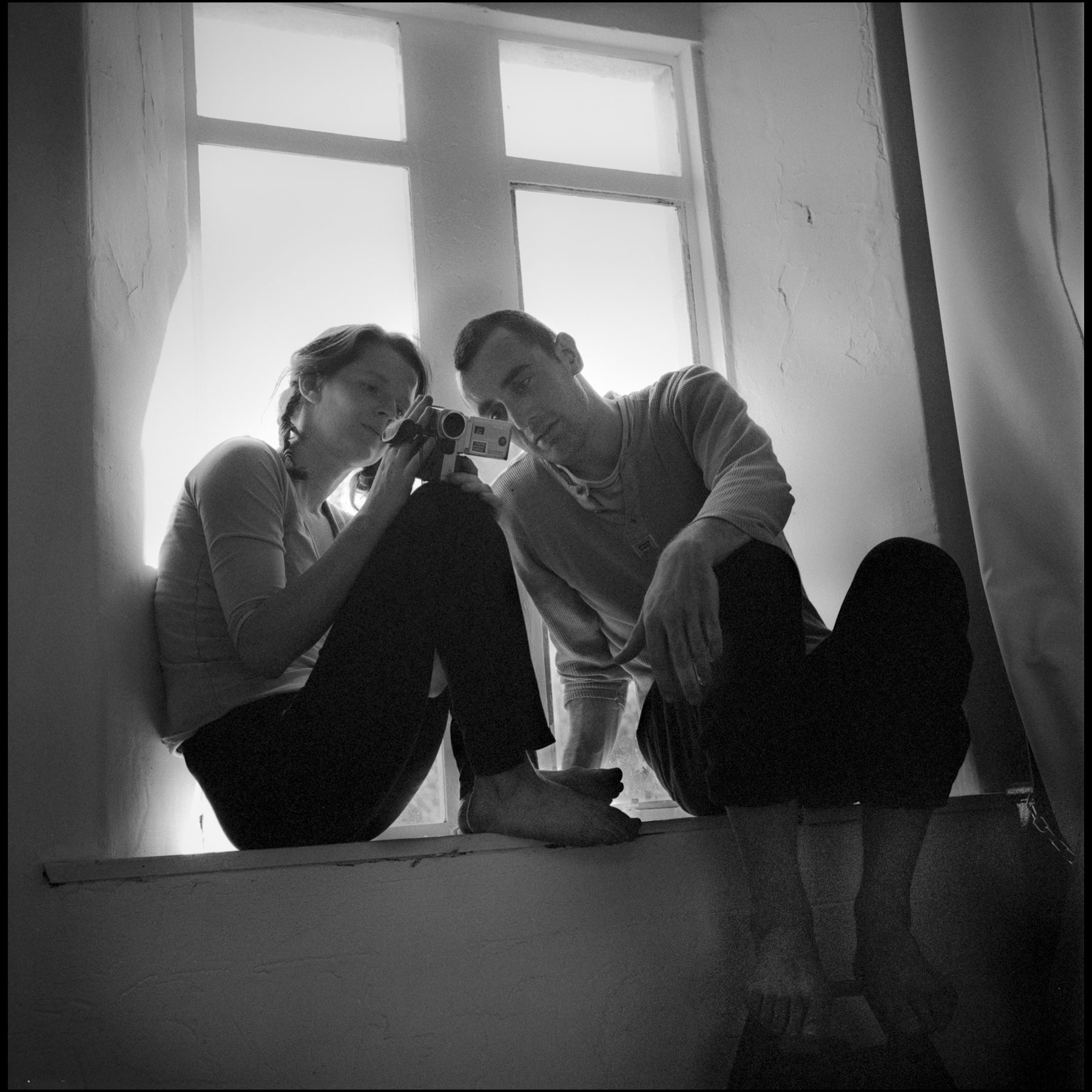 homme-femme-assis-sur-fenetre-regardent-camera-video-noir-et-blanc