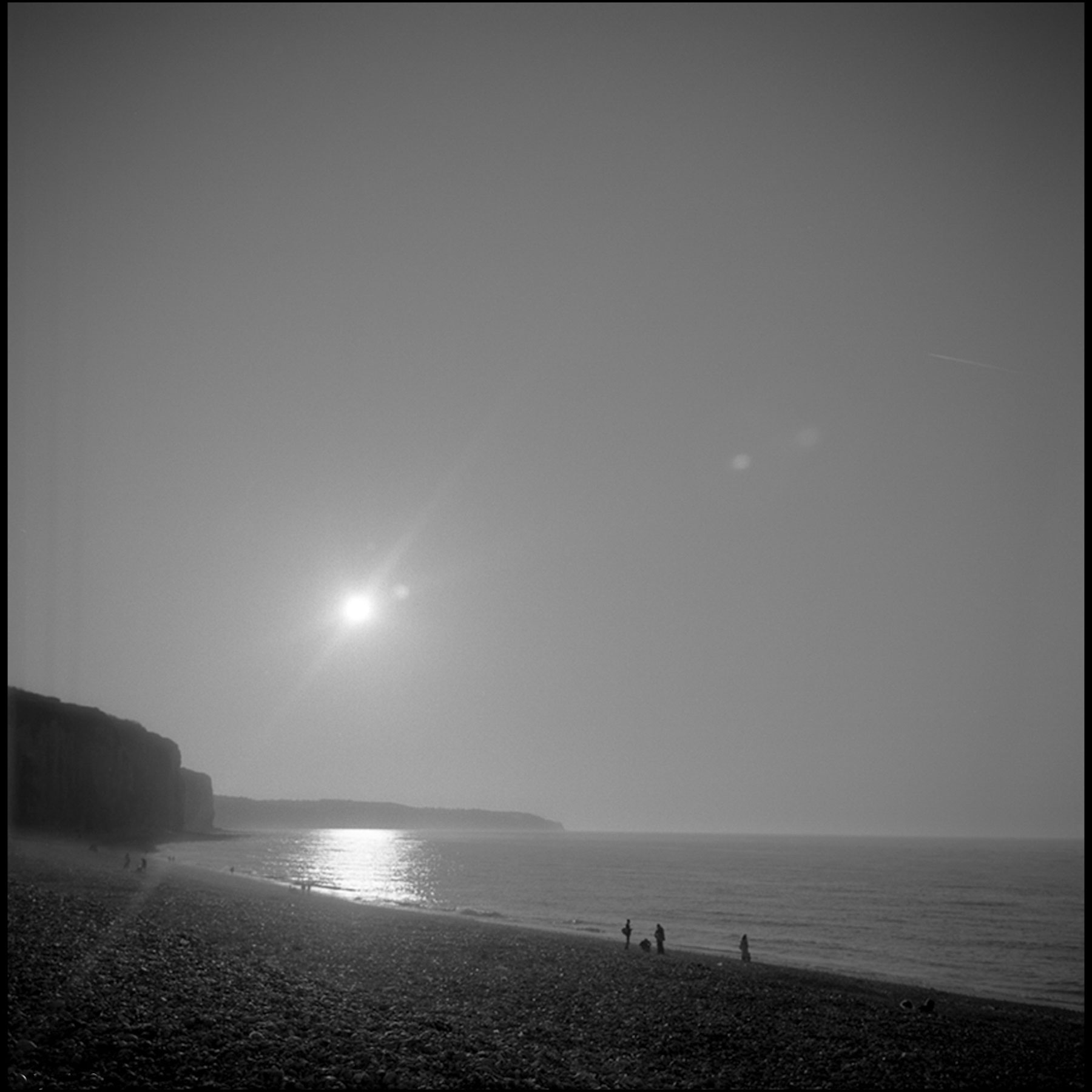 plage-personnes-au-loin-falaises-soleil-noir-et-blanc