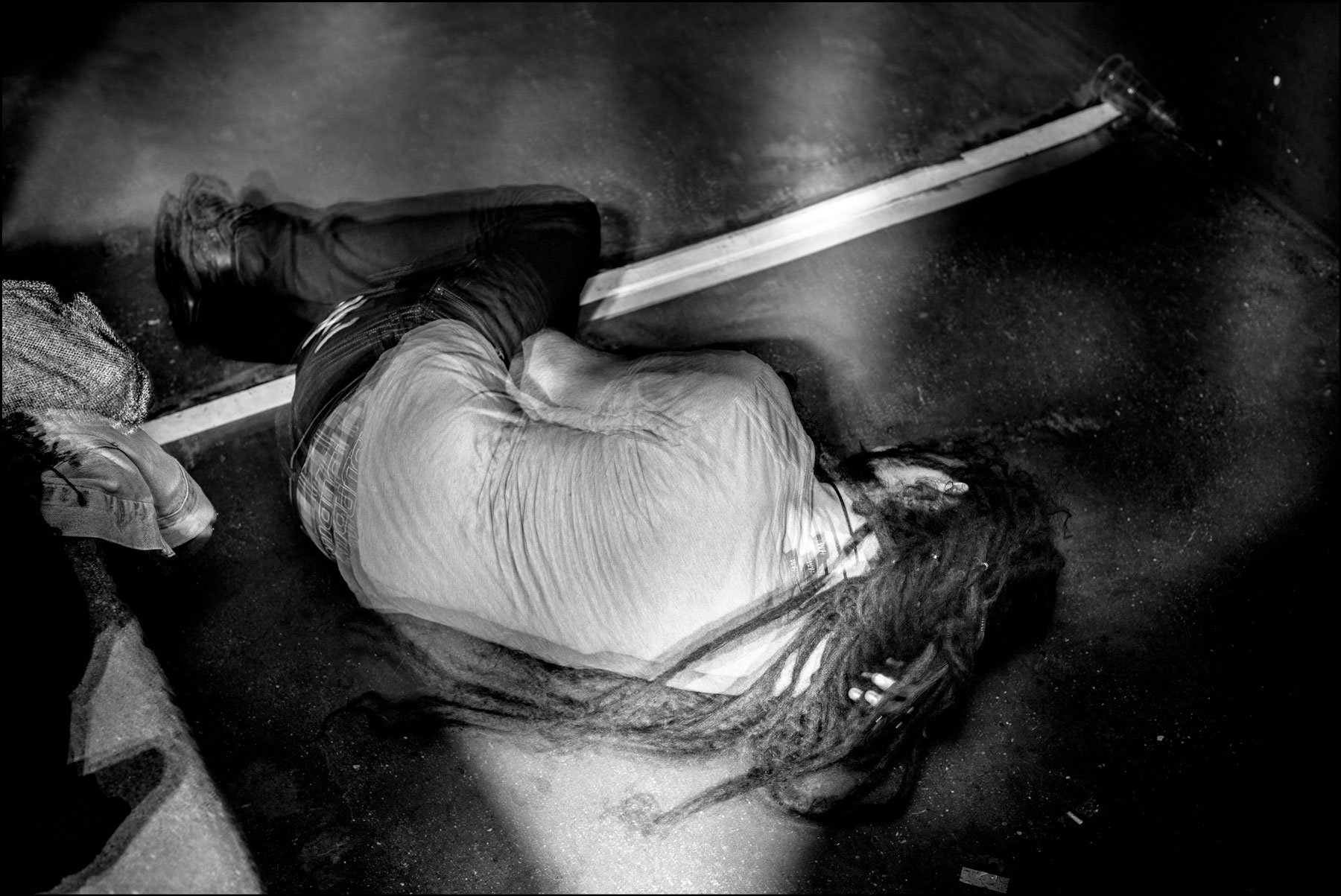 homme-dreadlocks-position-foetale-sur-sol-de-dos-noir-et-blanc